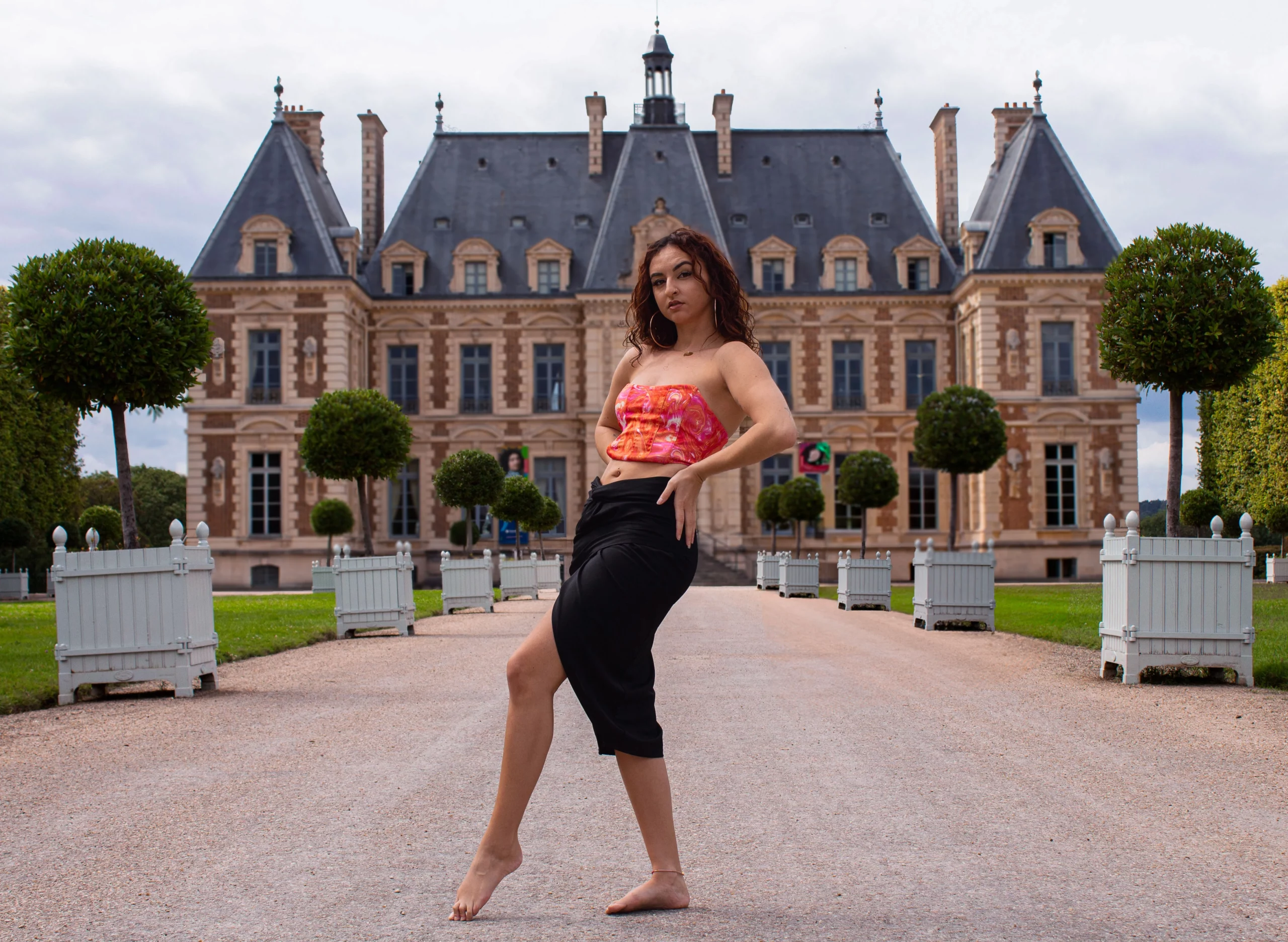 Portrait d’une femme posant dans une allée du parc de Sceaux avec le château en arrière-plan