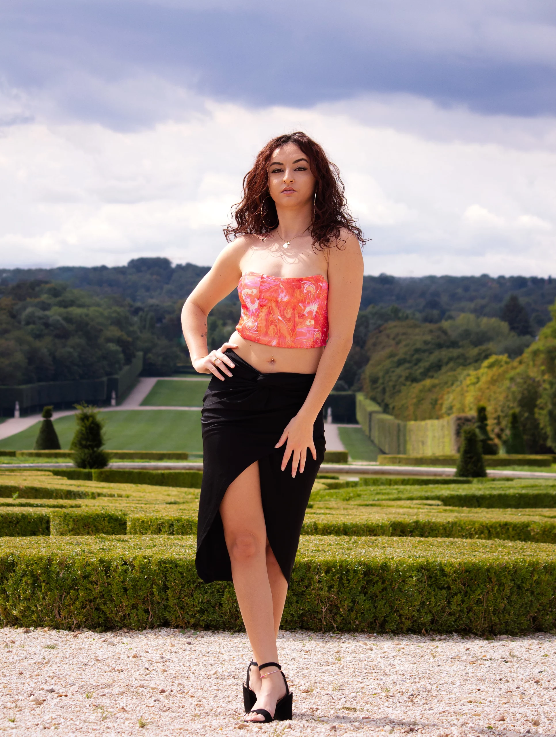 Jeune femme posant dans les jardins du château de Sceaux avec les allées et parterres de verdure en arrière-plan