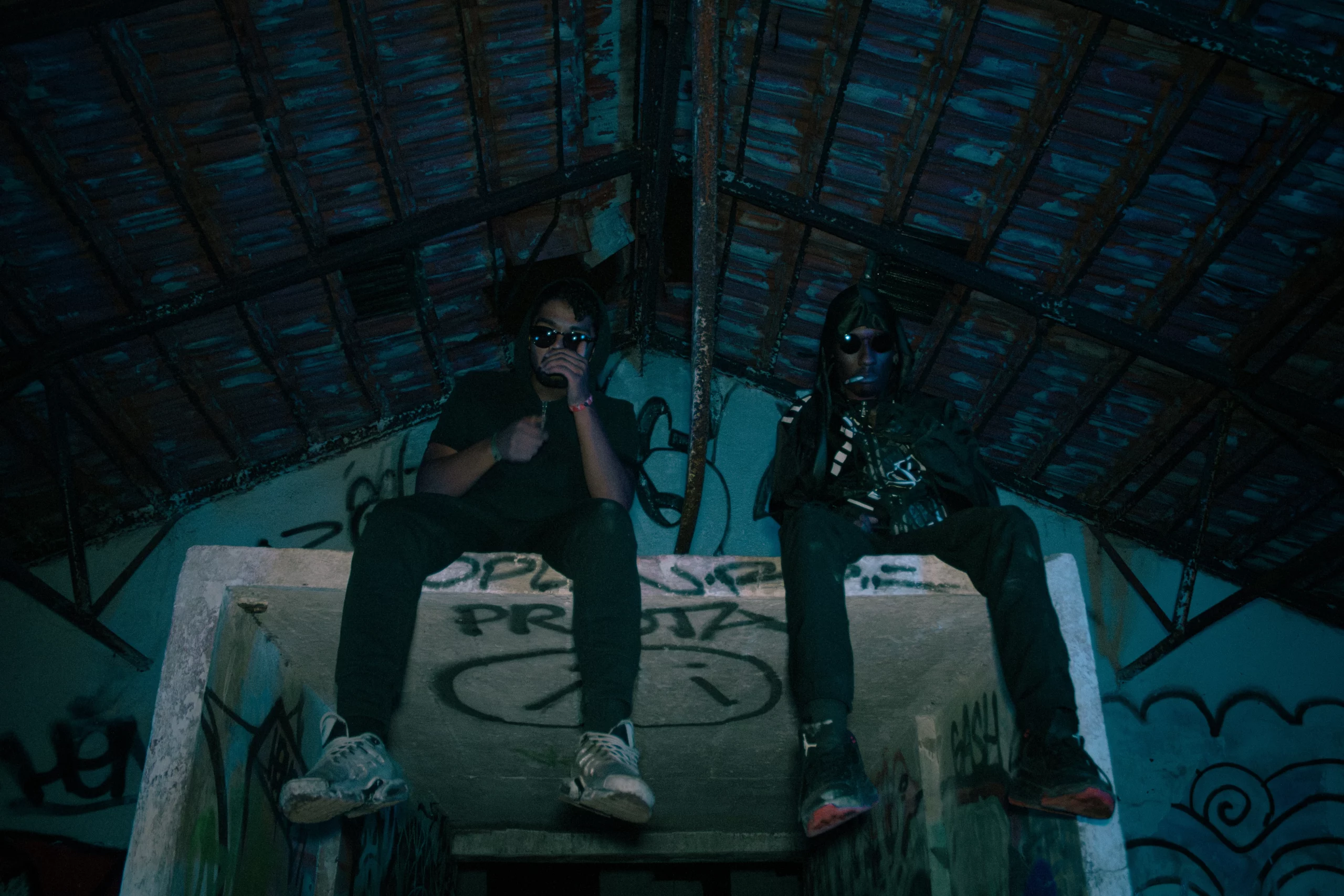 Photo d’un duo rap en ambiance urbaine sombre, style underground, entre ombre et lumière.
