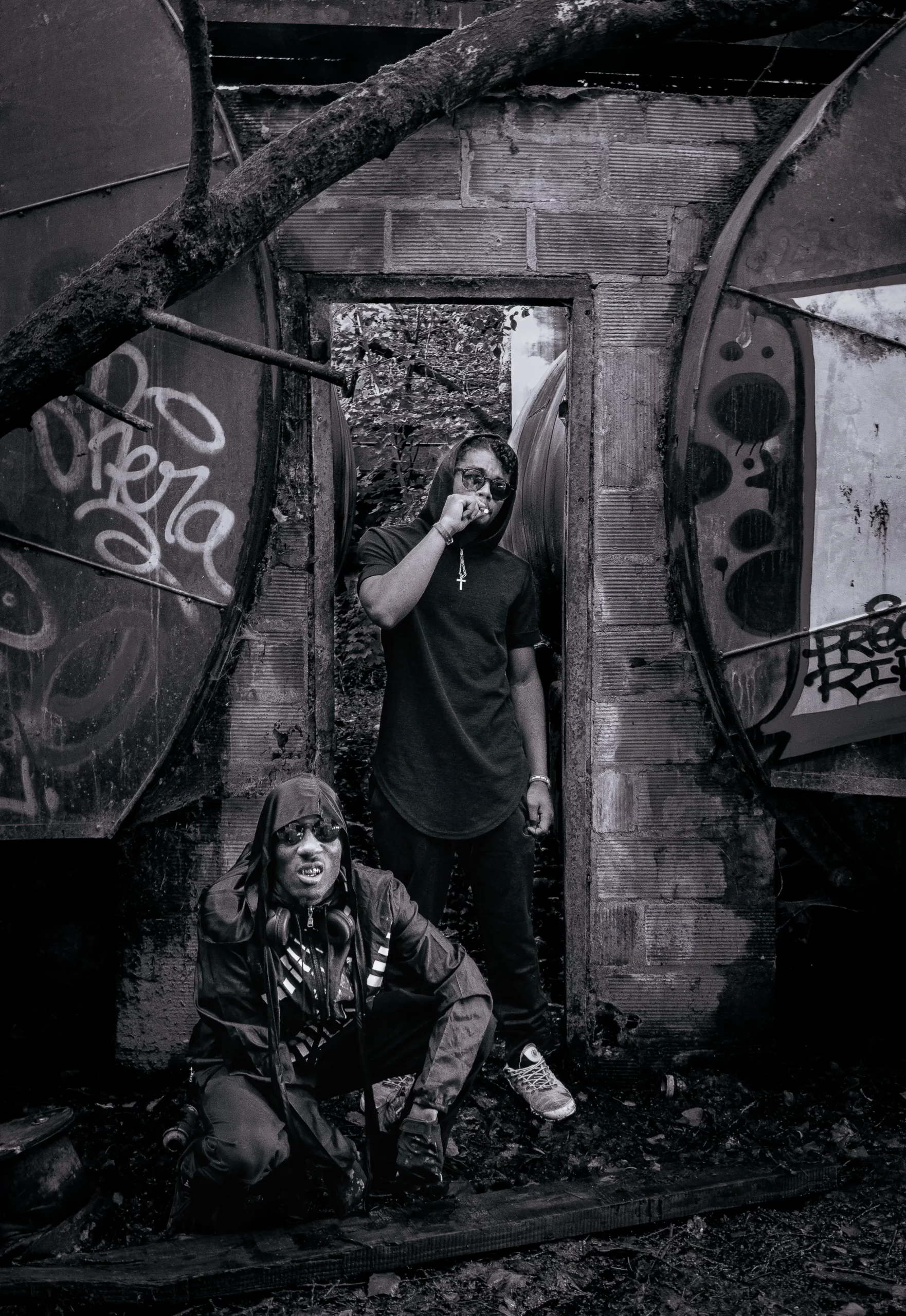 Deux hommes posent dans une friche taguée, style sombre et assumé, énergie brute et urbaine.