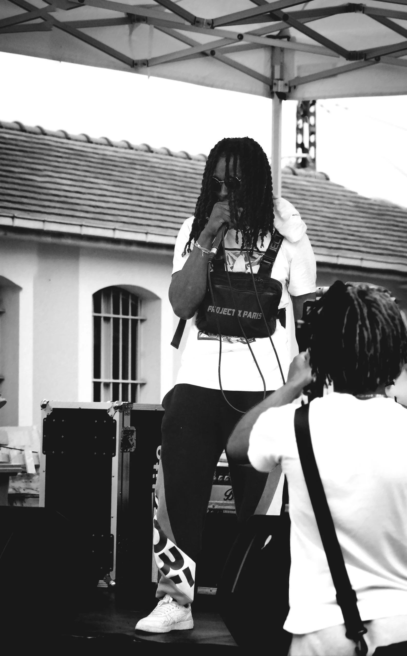 Photo noir et blanc d’un rappeur en concert, ambiance urbaine captée avec intensité.