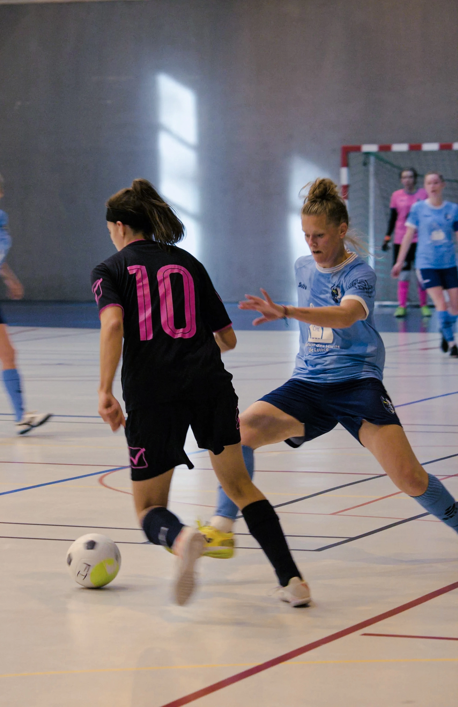 Photographie d'une joueuse de football en salle en train de dribbler son adversaire.