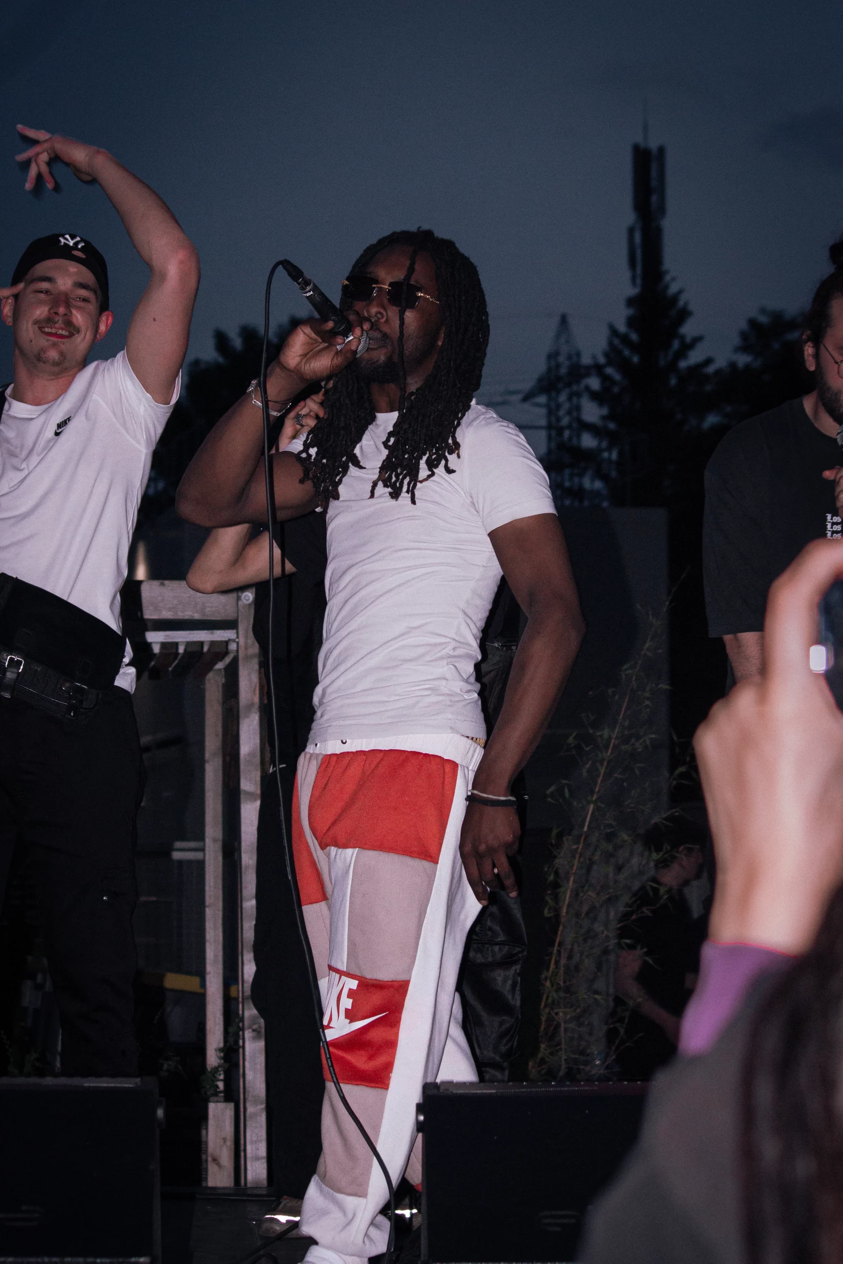 Photo de rappeur en live, ambiance hip-hop et complicité avec le public sous les lumières de scène.