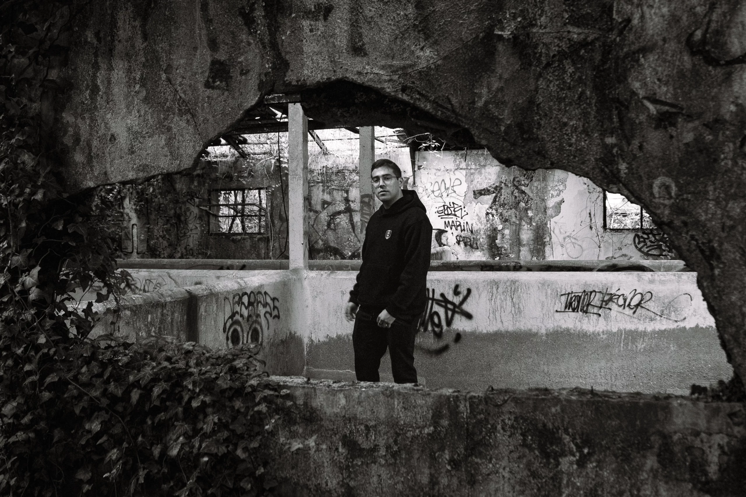 Photographie d'un homme en noir et blanc prise à travers un trou dans un mur.