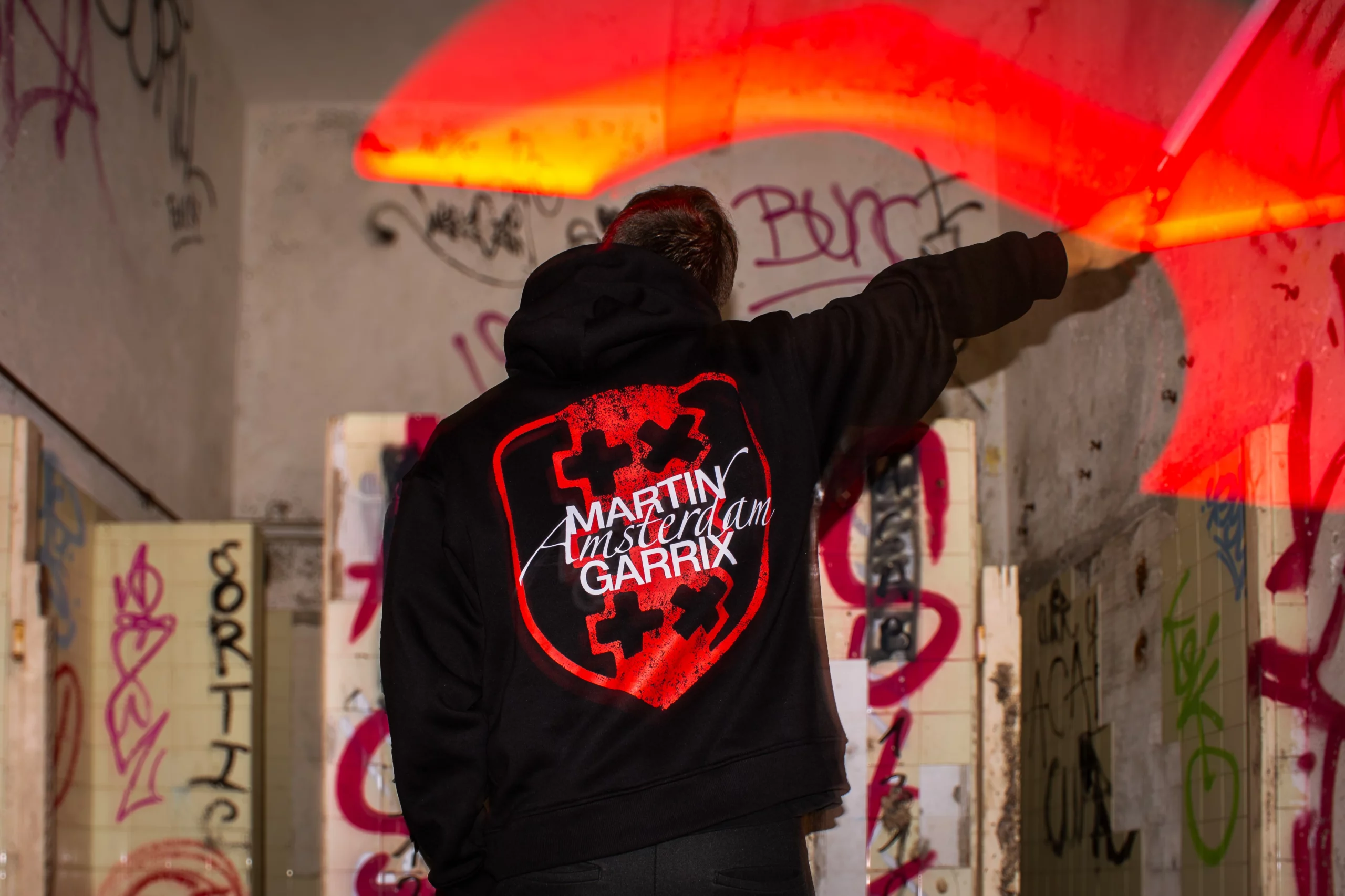 Photographie en lightpainting d'un homme tenant une lumière rouge dans la main.